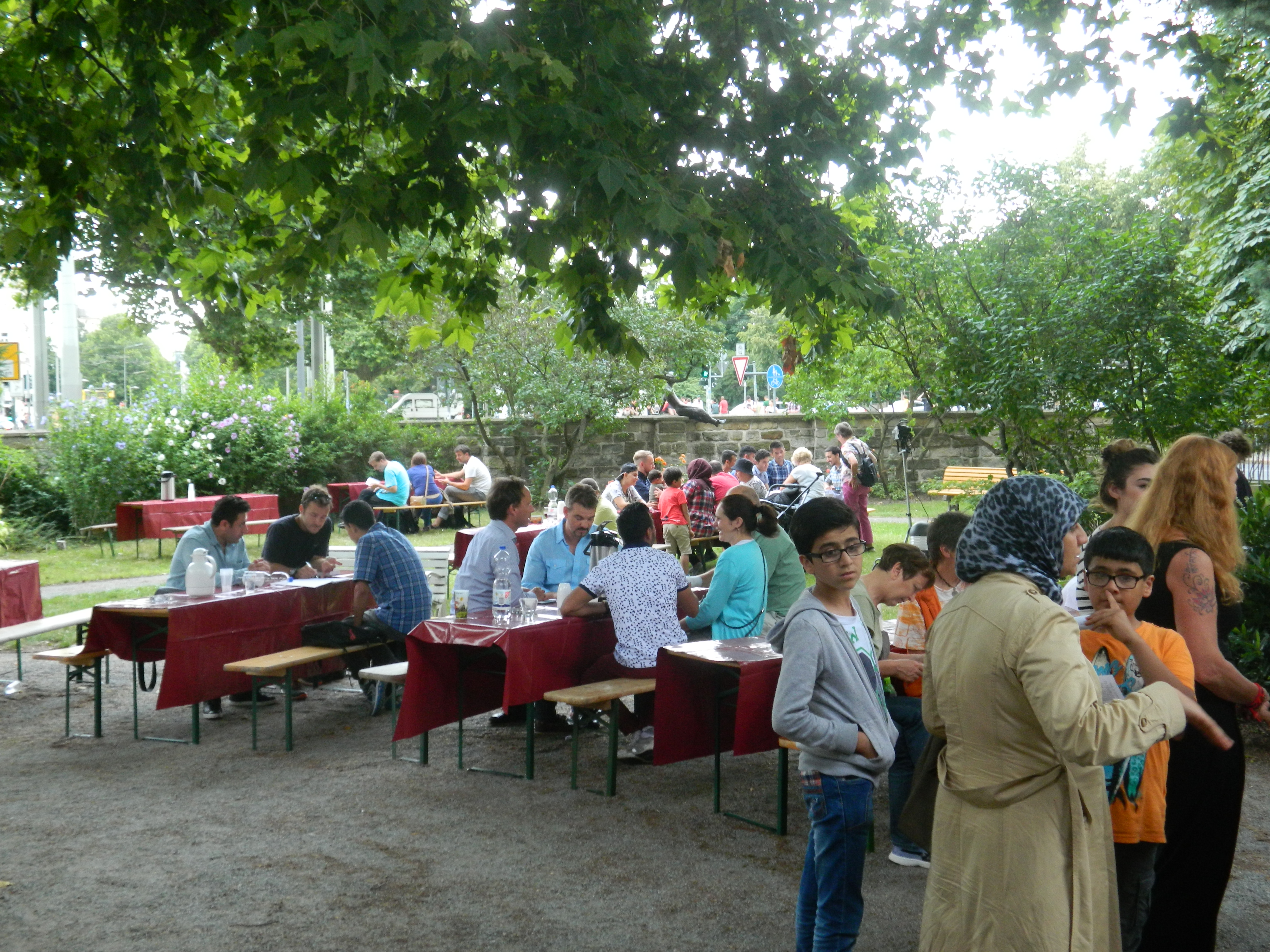 Tische im Freien, Menschen stehen in Gruppen